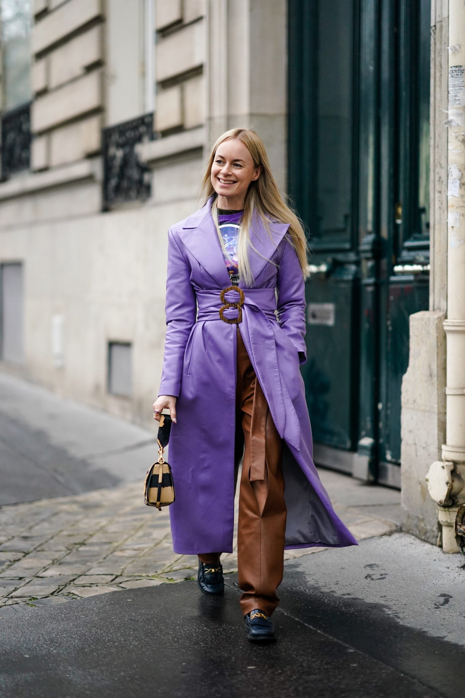 Woman styling a purple leather trench coat with chocolate-brown trousers