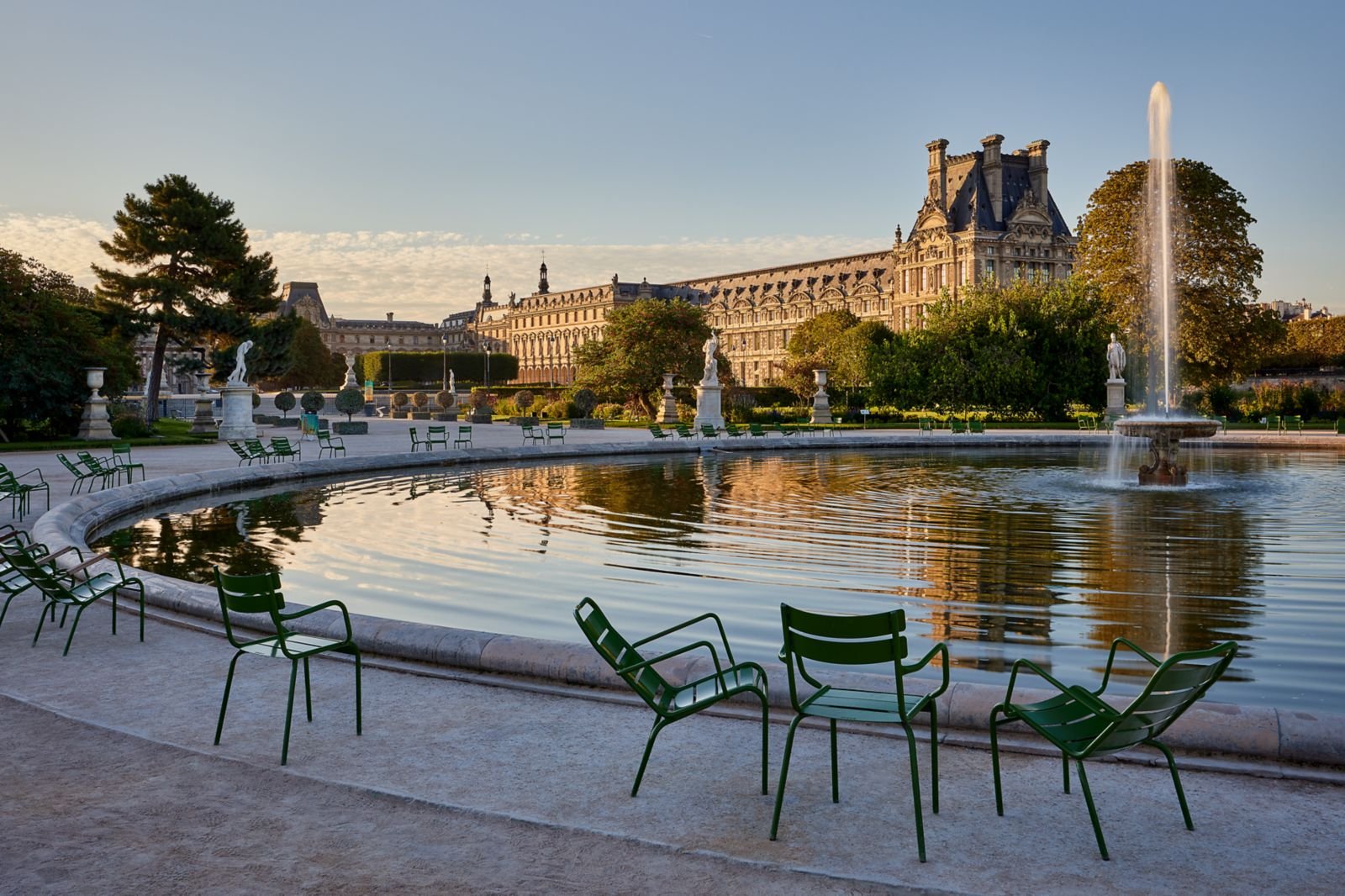 Green chairs beside a Tuileries Garden basin.