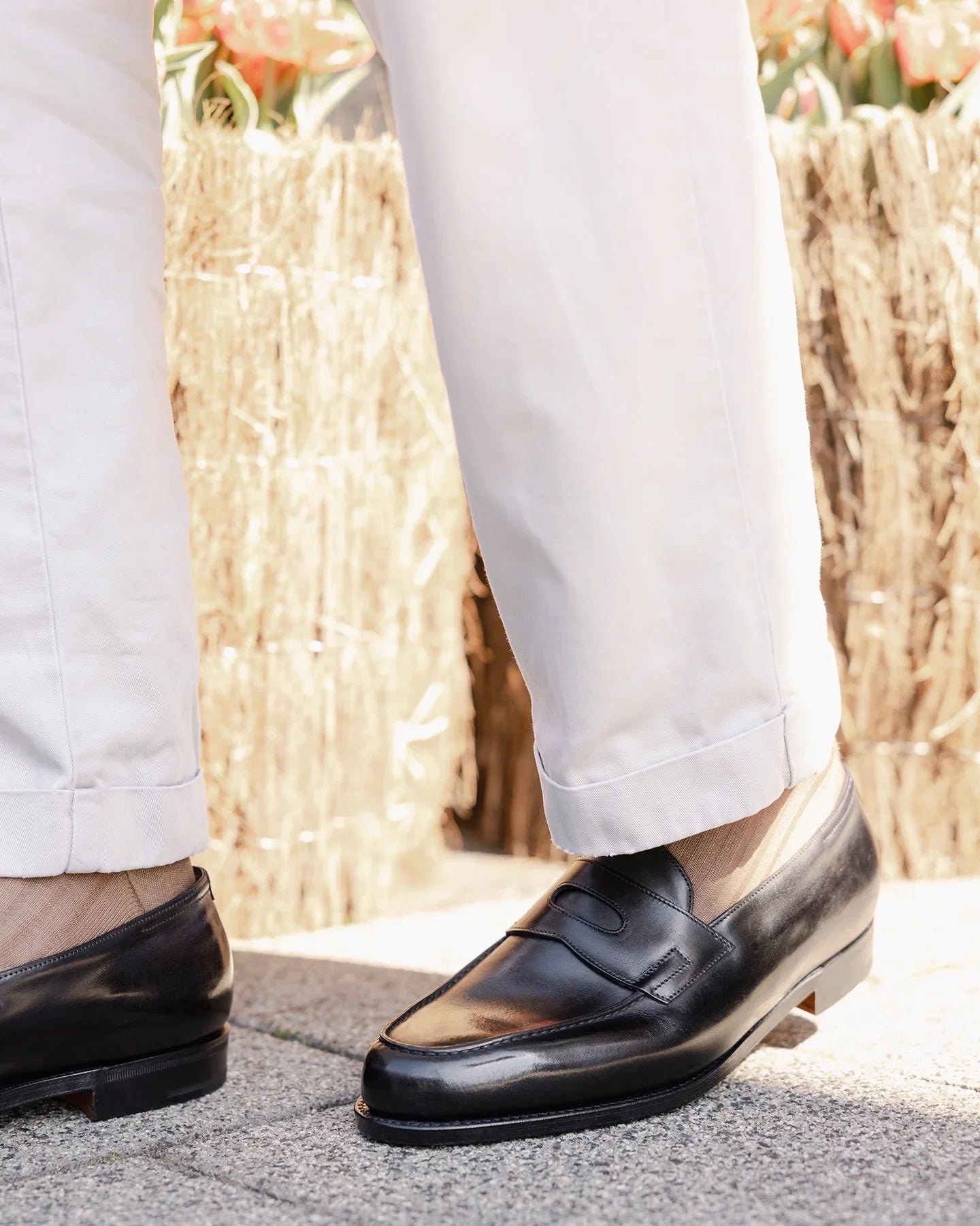 John Lobb Lopez black penny loafers worn with light tailored trousers.