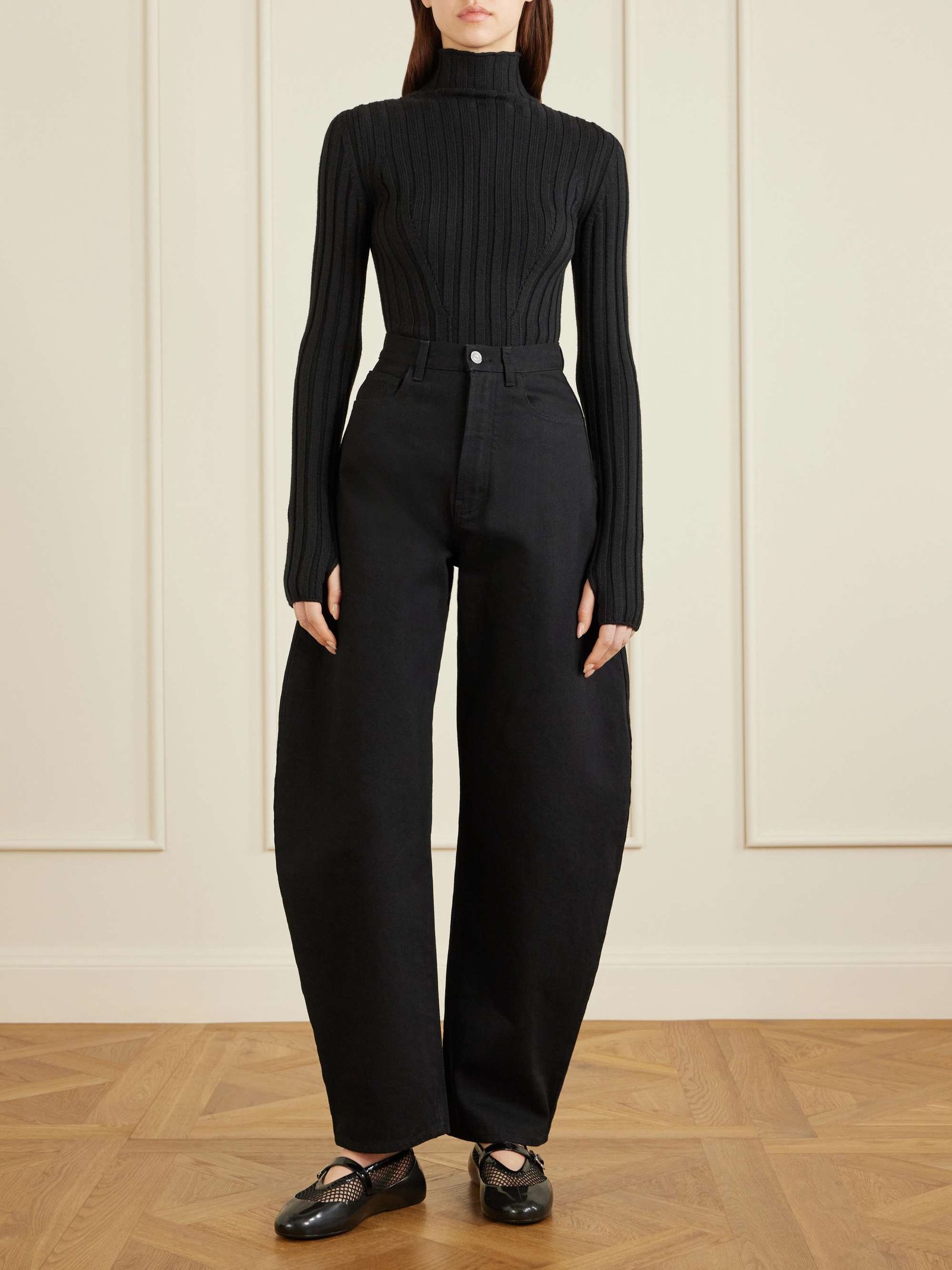 Model wearing black mesh ballet flats with a fitted top and tailored trousers.